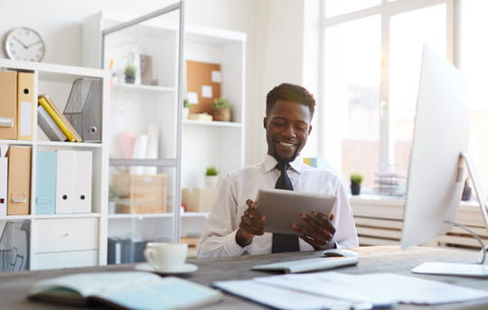 Businessman at desk looks at tablet