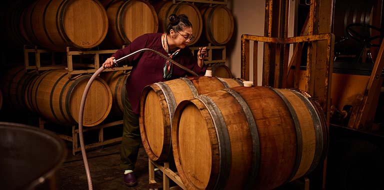 Wine maker tasting wine from barrel