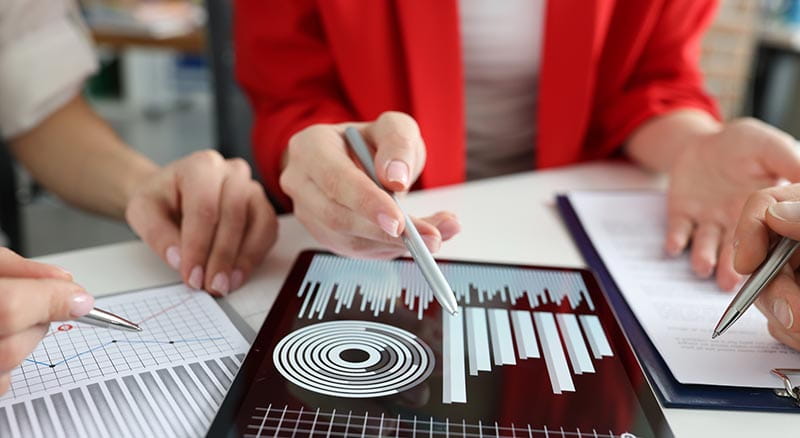 Person looking at tablet with pen and graphs