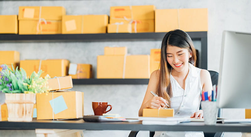 Businesswoman addressing packages to be sent out