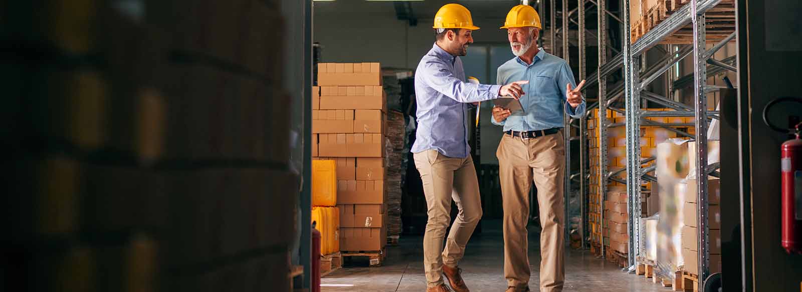 Colleagues walking and talking in warehouse with boxes