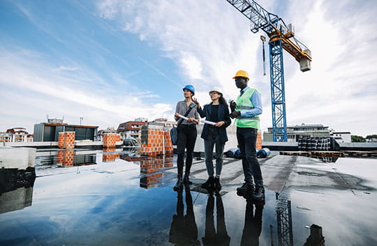 Workers reviewng items on the roof of a construction site.
