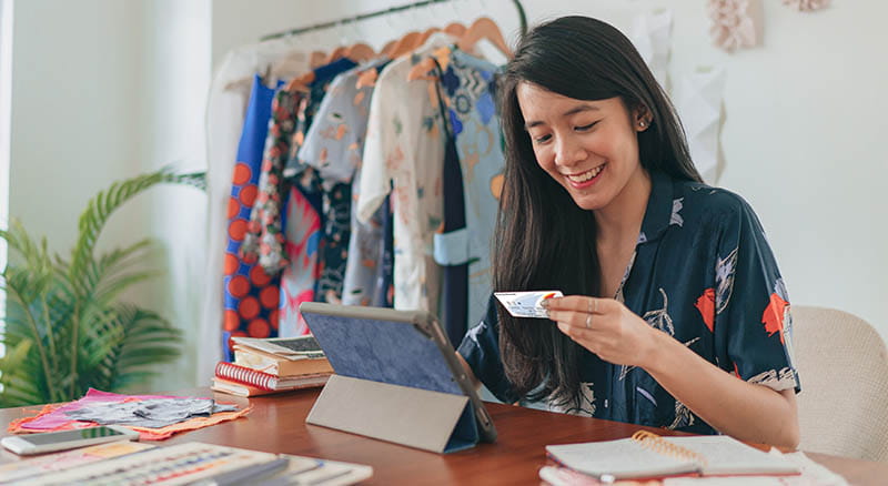 Person at desk looking at tablet with card in hand