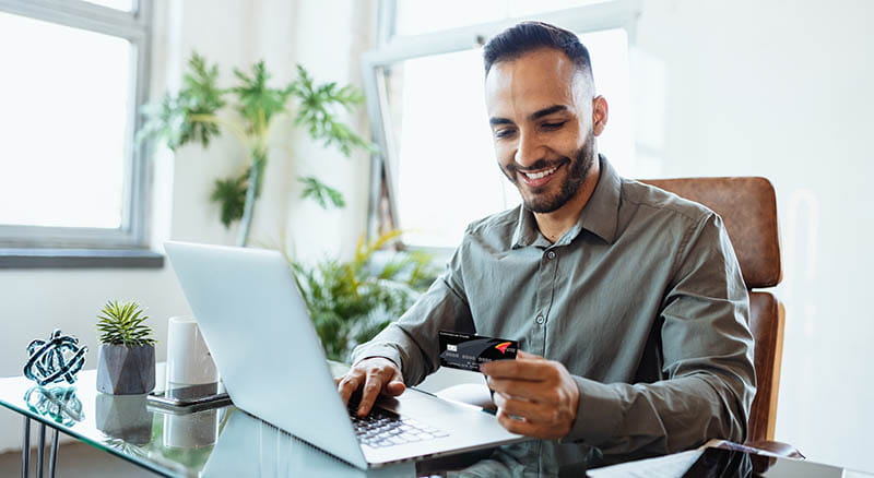 Person on computer looking at credit card