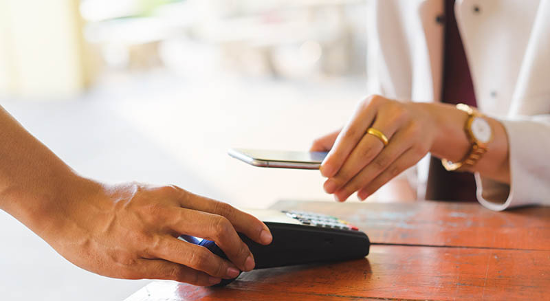 Person paying at a card reader with a phone