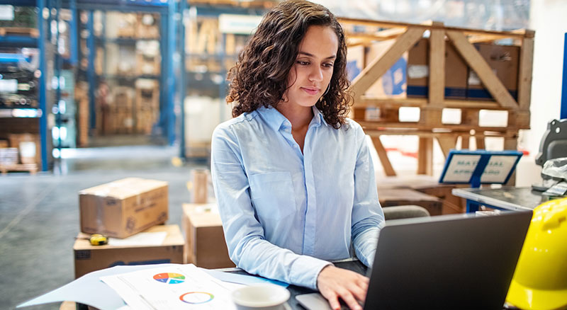 Woman in warehouse working on laptop