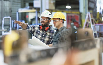 Two workers talking with hard hats in warehouse