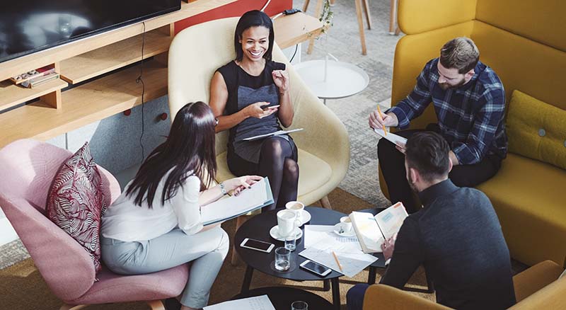 Colleagues chatting in open workspace on devices