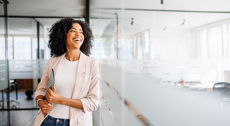 person smiling and walking through office with laptop