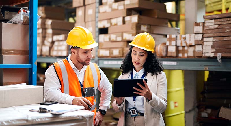 Colleagues looking at tablet in discussion in a warehouse