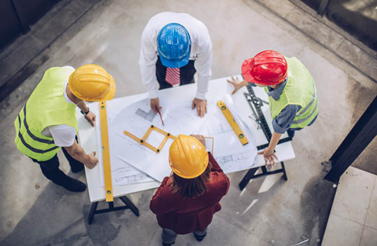 Aerial view of four people in hard hats reviewing construction plans