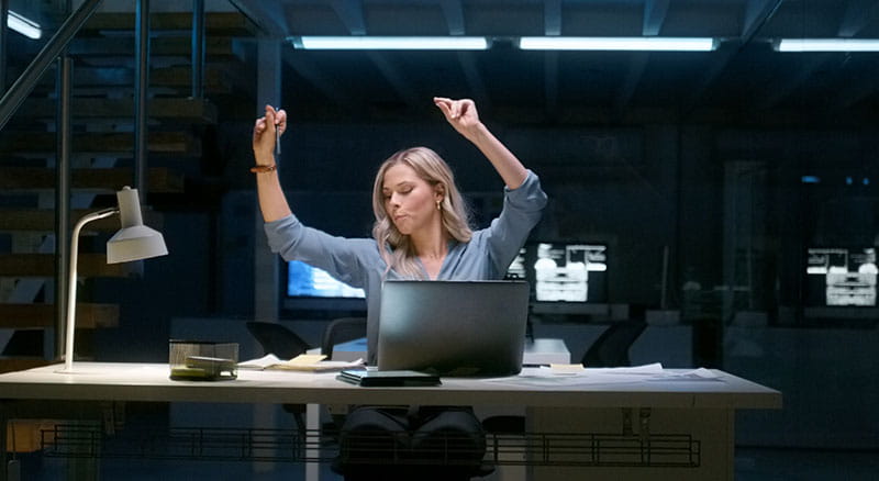 Person celebrating at computer in dark office