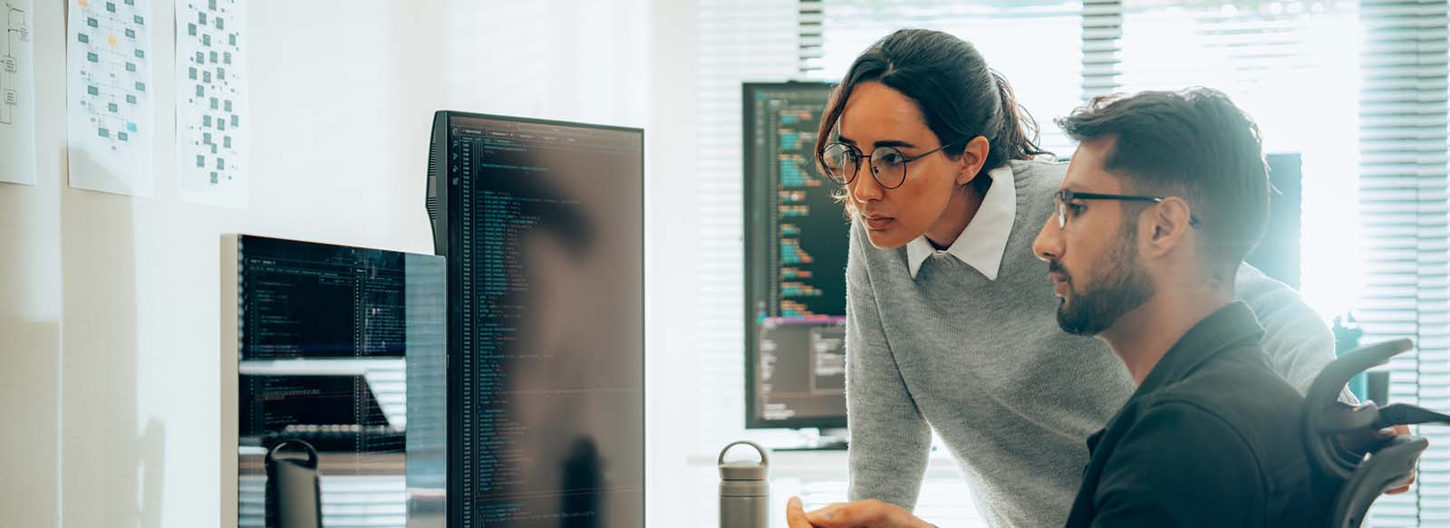 Two colleagues in an office space looking at a computer