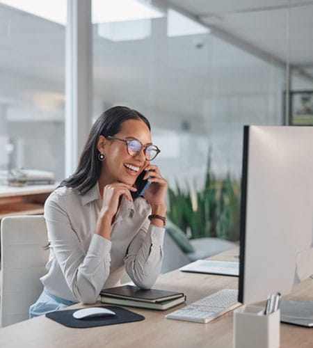 Person smiling while on the phone sitting at a computer