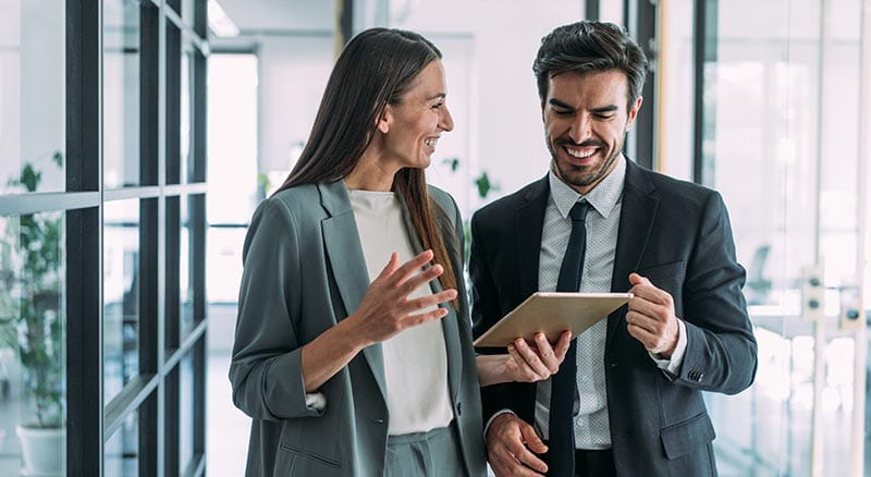 Two colleagues walking and talking with tablet in hand
