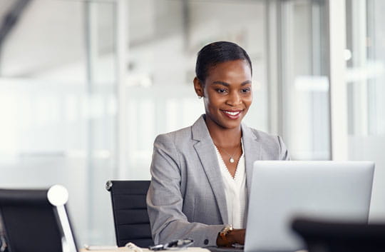 Smiling business woman works on laptop