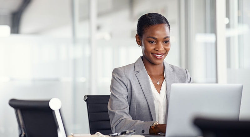 Smiling business woman works on laptop