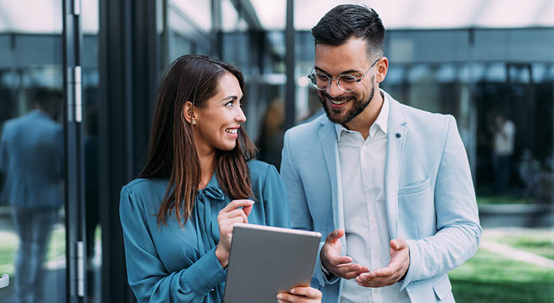 Two people walking and looking at tablet