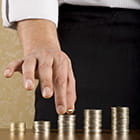 White male hand stacking quarters in progressively taller columns