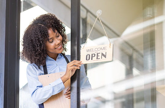 Person changing a shop sign to open
