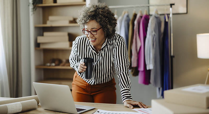 Person holding coffee and looking at laptop
