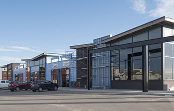 Strip mall under construction with flat angled roofs a few trucks in the parking lot and blue skies