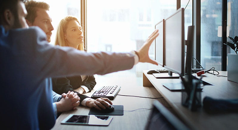 Photo of professionals pointing and looking at a row of computers