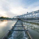 Photo of a water treatment plant at sunset with trough running through middle of body of water