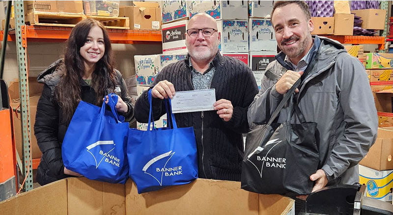 three people in a warehouse holding a check