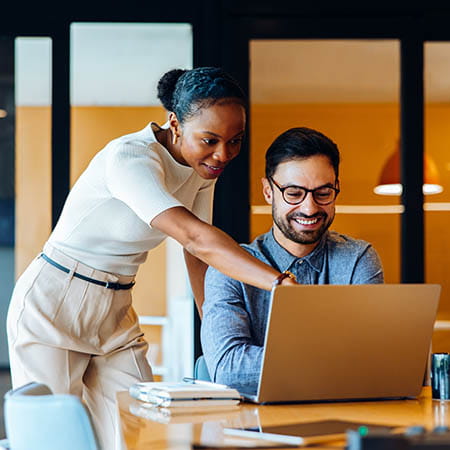 Two people pointing at laptop in office