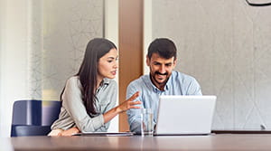 Two people at a table looking at a laptop