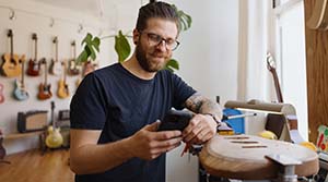 Person looking at phone and working on making a guitar