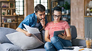 Two people looking at a tablet on the couch