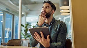 Person thinking with tablet in hand