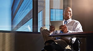 Person in an office smiling and looking at a tablet