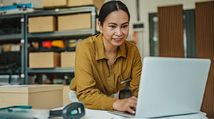 Woman on laptop with scanner and boxes