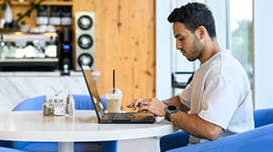Person on a laptop with a drink in a coffee shop