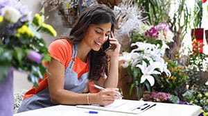 Person in flower shop on phone looking at clipboard