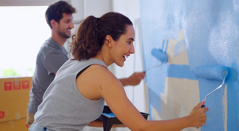 Two people painting a wall blue