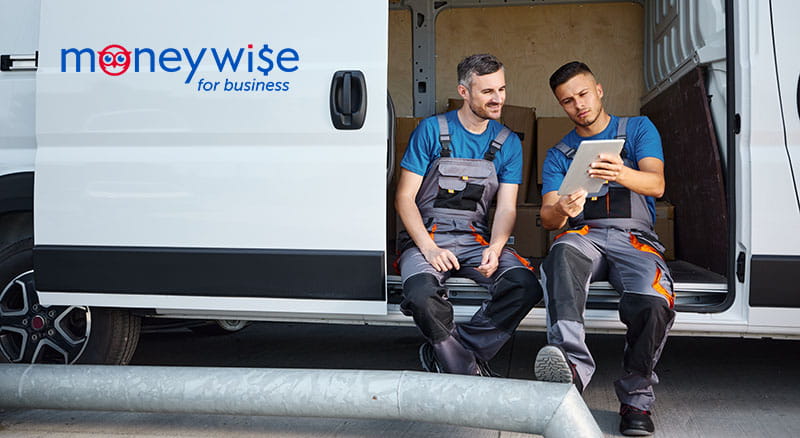 Moneywise logo on van with two people looking at tablet in door