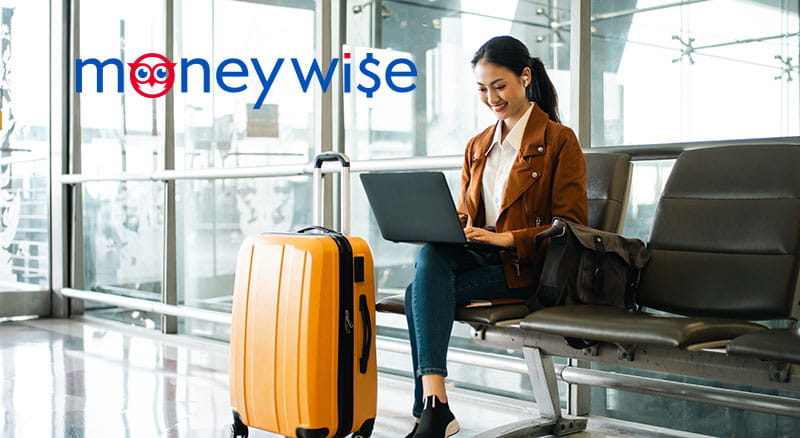 Person on a laptop waiting in an airport with luggage