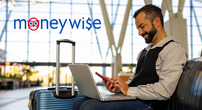 Person using a laptop and phone with a suitcase in an airport
