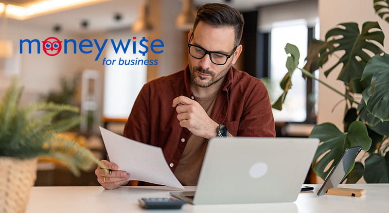 Person looking at paper and laptop with MoneyWise for business logo