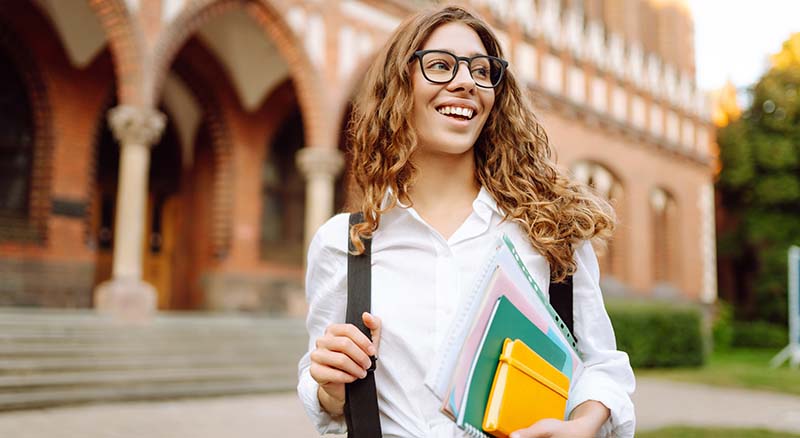 Person on campus with backpack and notepads