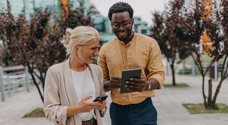 Colleagues smiling and looking at devices