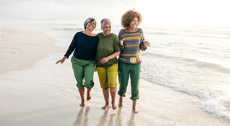 Three people walking and laughing on the beach