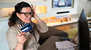 Woman on computer with card in hand