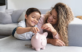 Mother and child putting coins in piggy bank