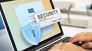 Pair of hands using a laptop with pop out image of a cyber security lock and the word security in a pop up next to the lock