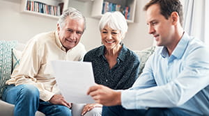 Older couple looking at a piece of paper being held by a younger male